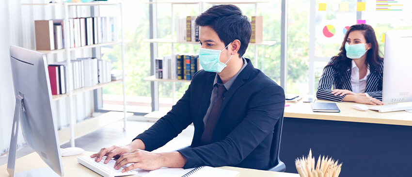 Two office workers wearing masks working during COVID-19