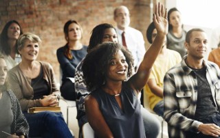 ragazza di colore che alza la mano perché cerca di farsi notare dal capo indifferente