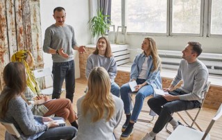 giovane business coaching che fa lezione a dipendenti seduti in una stanza