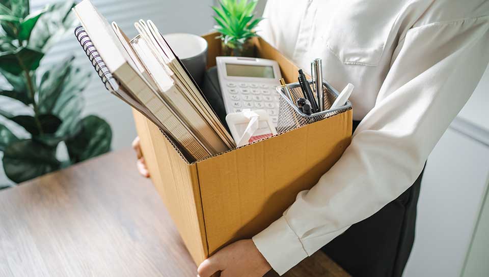 persona che raccoglie le sue cose in una scatola e lascia l'ufficio perché si è dimesso