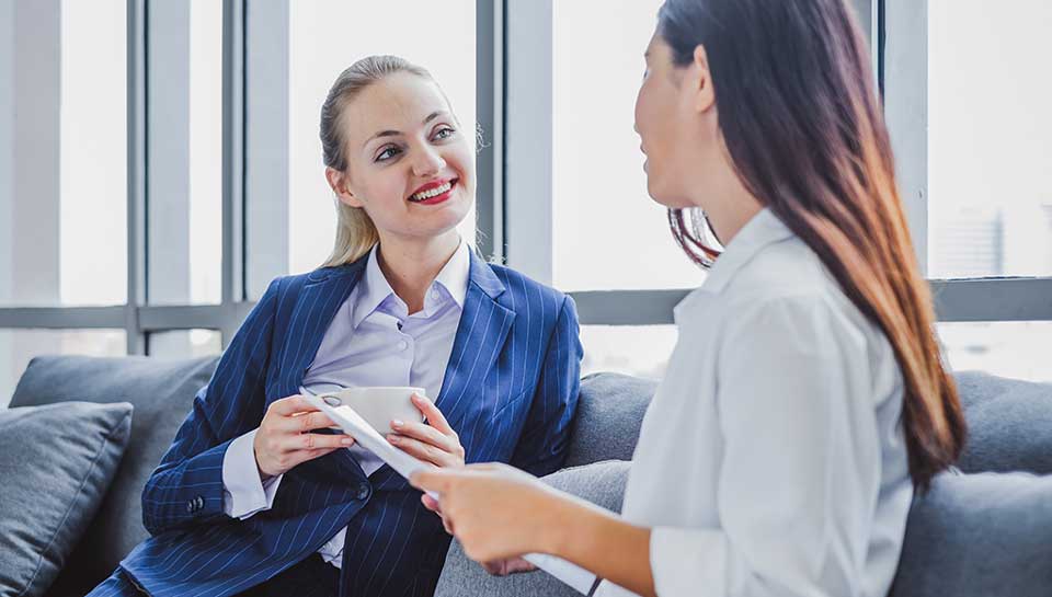 donne d'affari sedute su un divano che parlano di lavoro