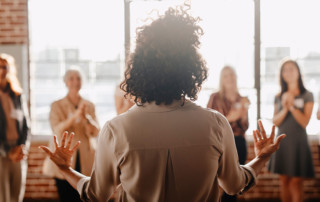 lavoratrice donna di spalle che parla a una platea di altre donne