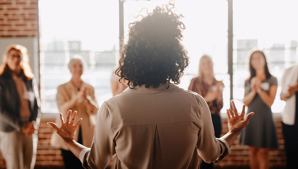 lavoratrice donna di spalle che parla a una platea di altre donne