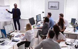 gruppo di ragazzi e ragazze a lezione con un docente di colore davanti alla lavagna