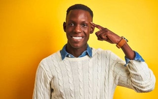 ragazzo di colore che si indica la testa con l'indice