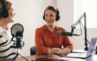 coppia di ragazze in studio che stanno registrando un podcast con microfoni e cuffie
