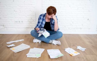 ragazza che è accovacciata a terra circondata da fogli sul pavimento