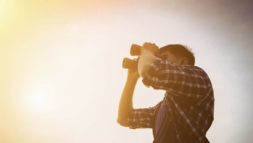 man looking in the horizon with binoculars