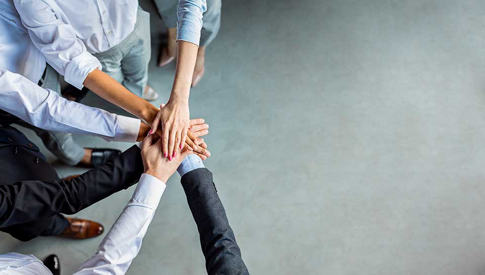 team che celebra l'unione mettendo le mani una sopra l'altra